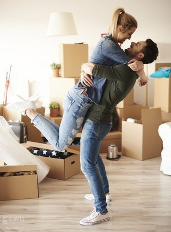 Junges Paar in neuer Wohnung umgeben von Umzugskartons